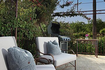 A chair with a blue pillow on it sits next to a grill