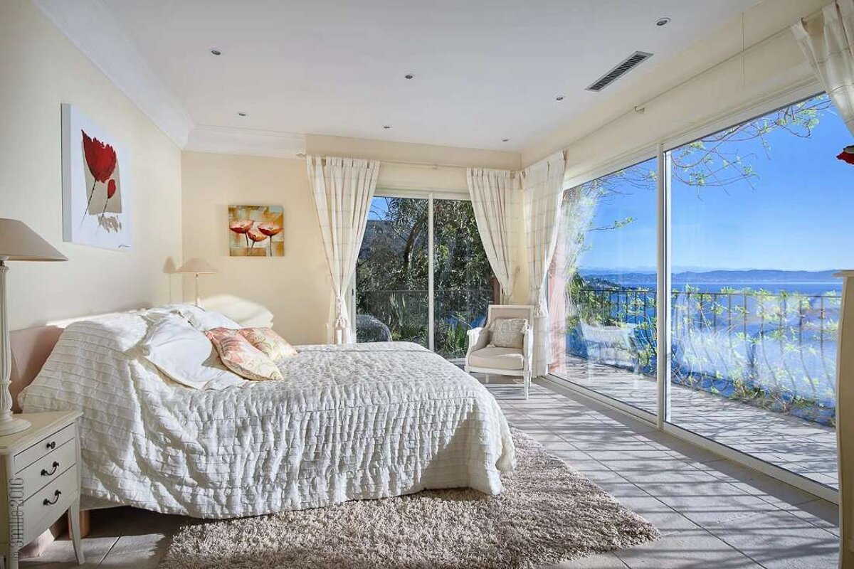 A bedroom with a large bed and a balcony overlooking the ocean