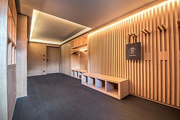 A black bag with the letter b on it hangs on a wooden wall