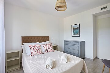 A bedroom with a bed and a dresser made in provence by janssens immobilier