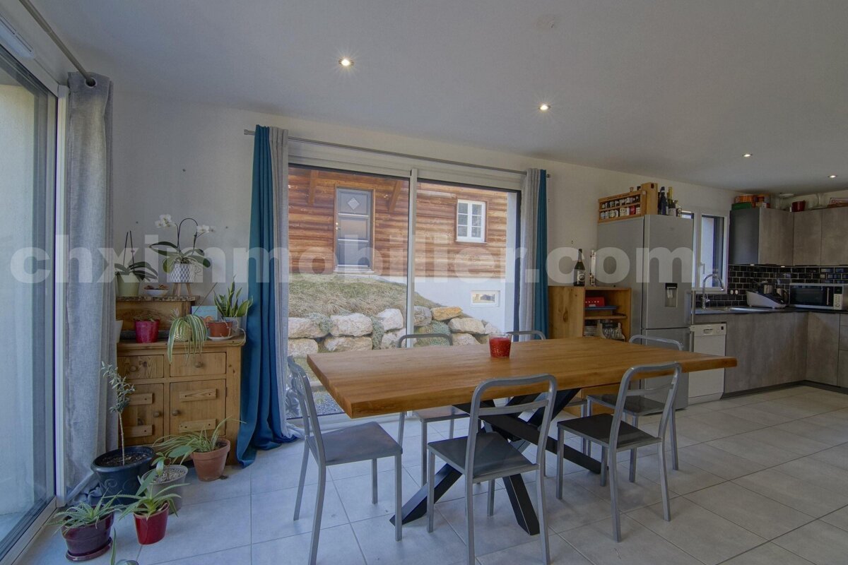 A dining room with a table and chairs and a sliding glass door that says chximmobilier.com