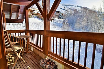 A wooden balcony with a view of snow covered mountains