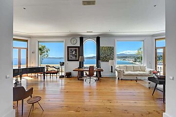 A living room with a clock on the wall and a view of the ocean
