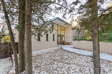 A house is surrounded by trees and gravel and has the word wasser on the bottom