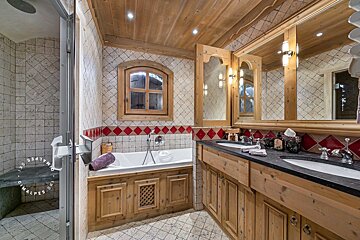 A bathroom with two sinks and a bathtub with a window