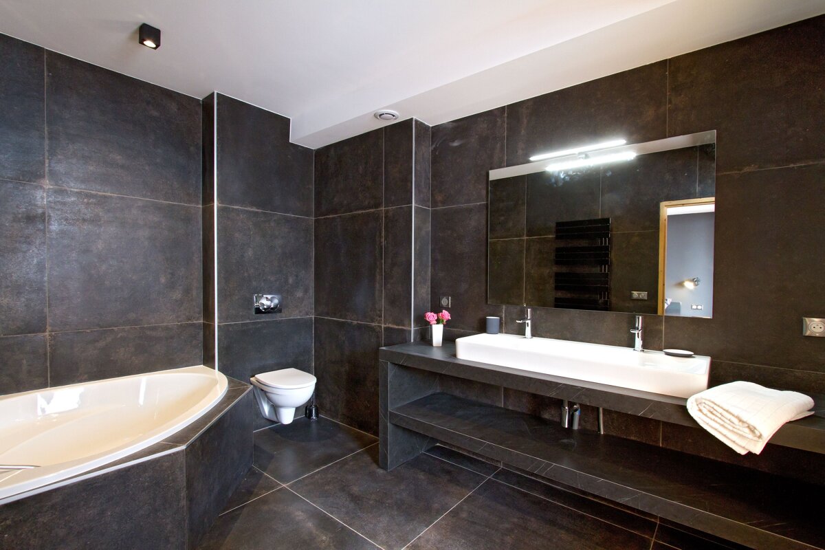 A bathroom with black tiles and a white sink