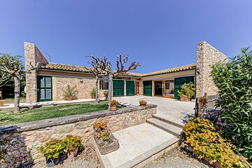 A stone house with green shutters and stairs leading up to it