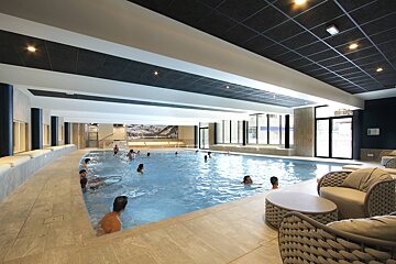 People are swimming in a large indoor swimming pool