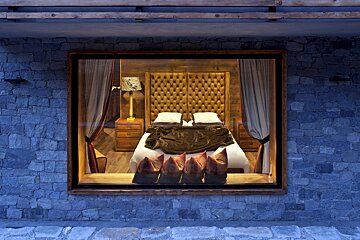 A bedroom with a bed and a lamp in the window