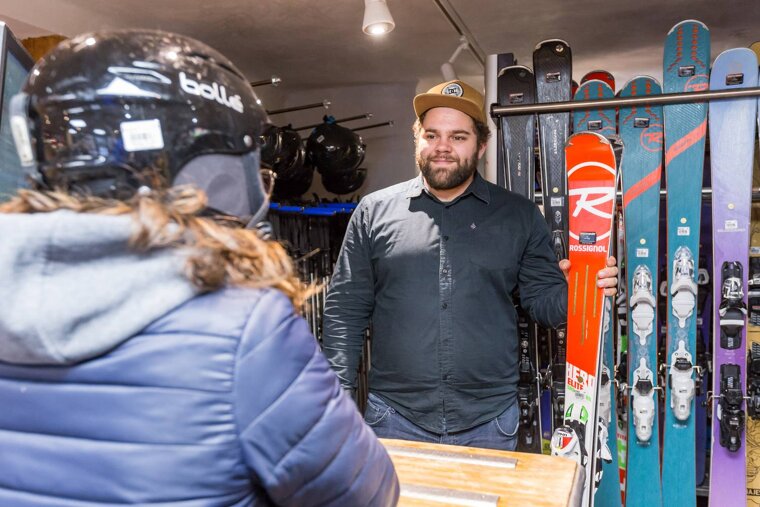 A man is holding a red rossignol ski in front of a woman