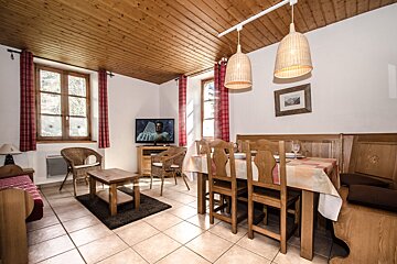 A living room with a table and chairs and a flat screen tv