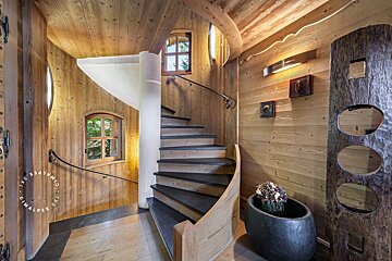 A spiral staircase in a wooden house with a sign that says ' alpes ' on it