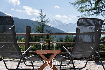 A bottle of wine sits on a table between two chairs