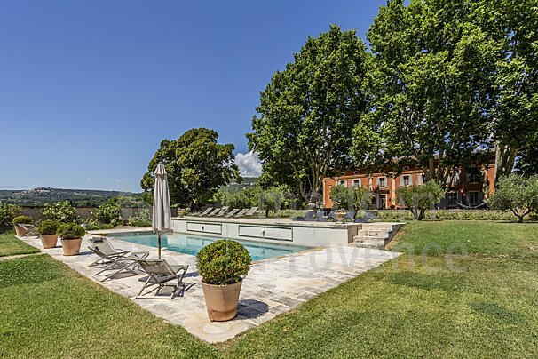 A large swimming pool is surrounded by lawn chairs and umbrellas