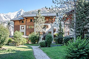 A brick walkway leads to a building with a mountain in the background