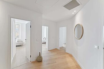 A white hallway with a round mirror on the wall
