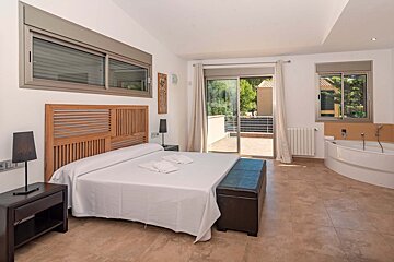 A bedroom with a large bed and a bathtub