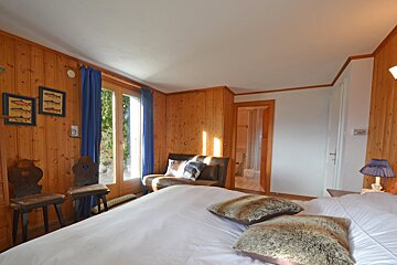 A bedroom with a bed a chair and a lamp