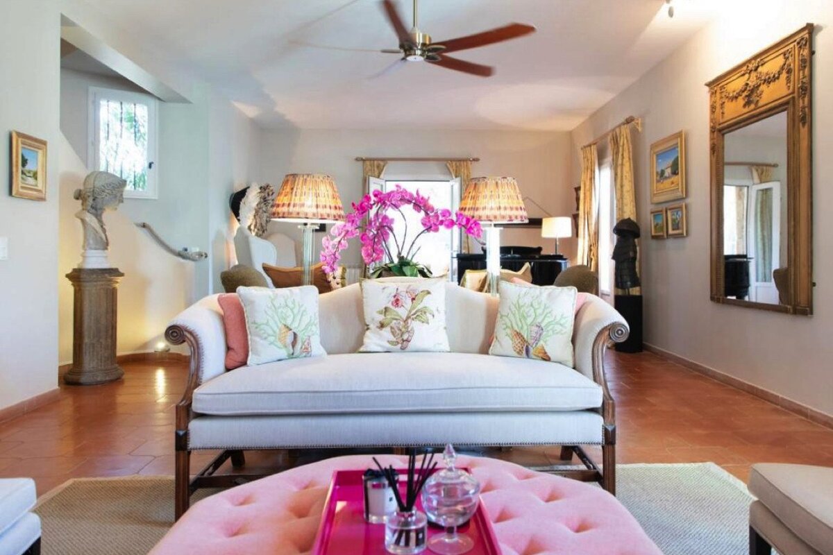 A living room with a white couch and pink ottoman
