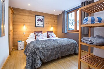 A bedroom with a bed and a shelf with towels on it