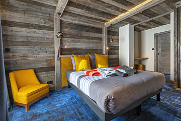 A bedroom with a large bed and a yellow chair