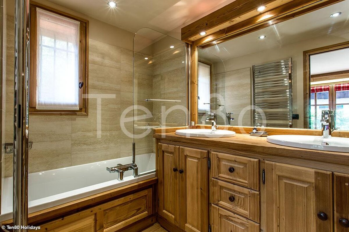 A bathroom with two sinks and a bathtub with the word ten80 holidays in the corner