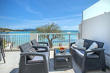 A balcony with a couch and chairs overlooking the ocean
