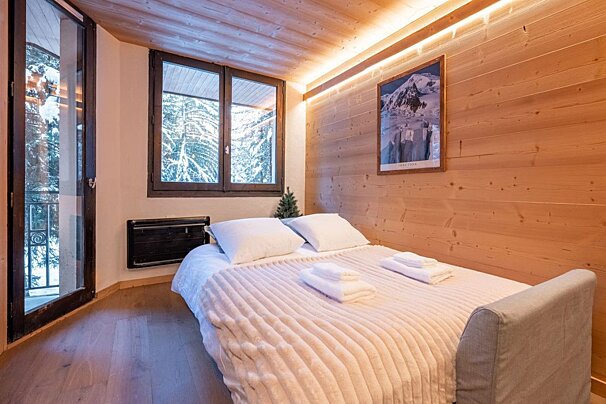 A bedroom with a bed and a picture of a mountain on the wall