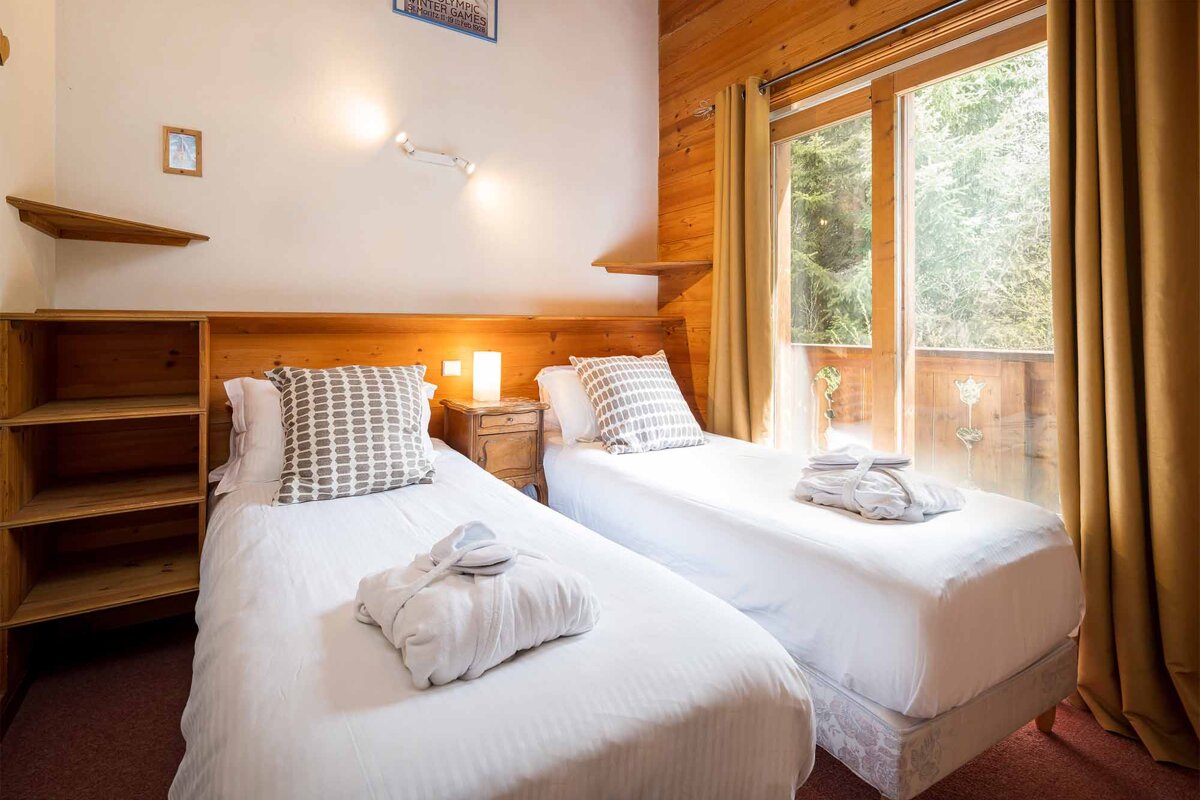 A bedroom with two twin beds and a window