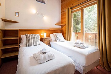 A bedroom with two twin beds and a window