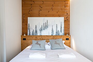 A bed with a painting of trees above it
