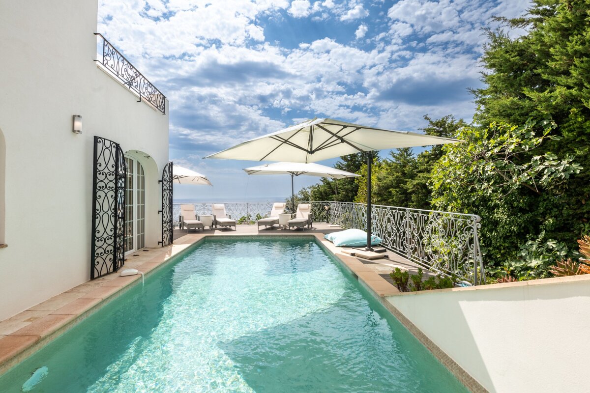 A large swimming pool is surrounded by chairs and umbrellas