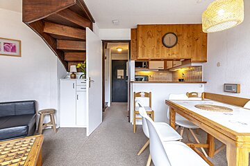 A living room with a table and chairs and a clock on the wall