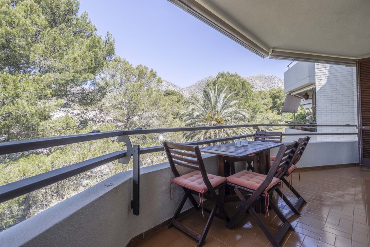 A balcony with a table and chairs and mountains in the background