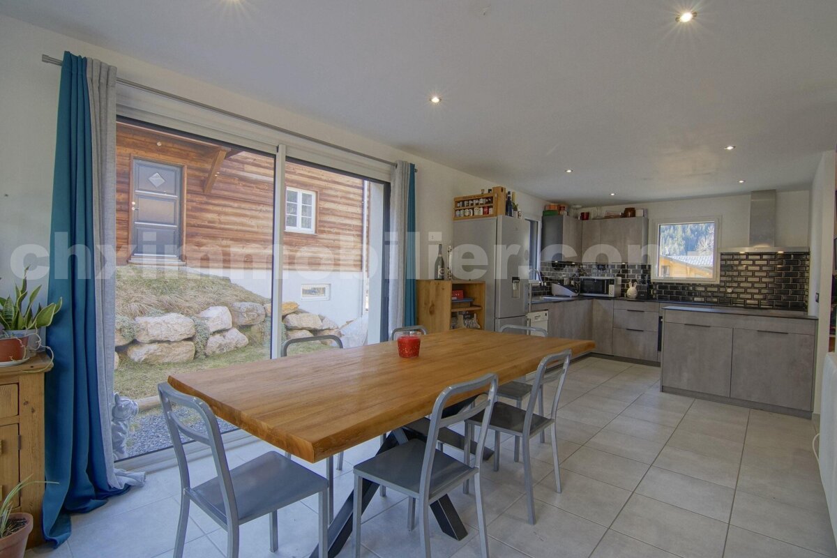 A dining room with a wooden table and chairs and a sign that says immobilier.com