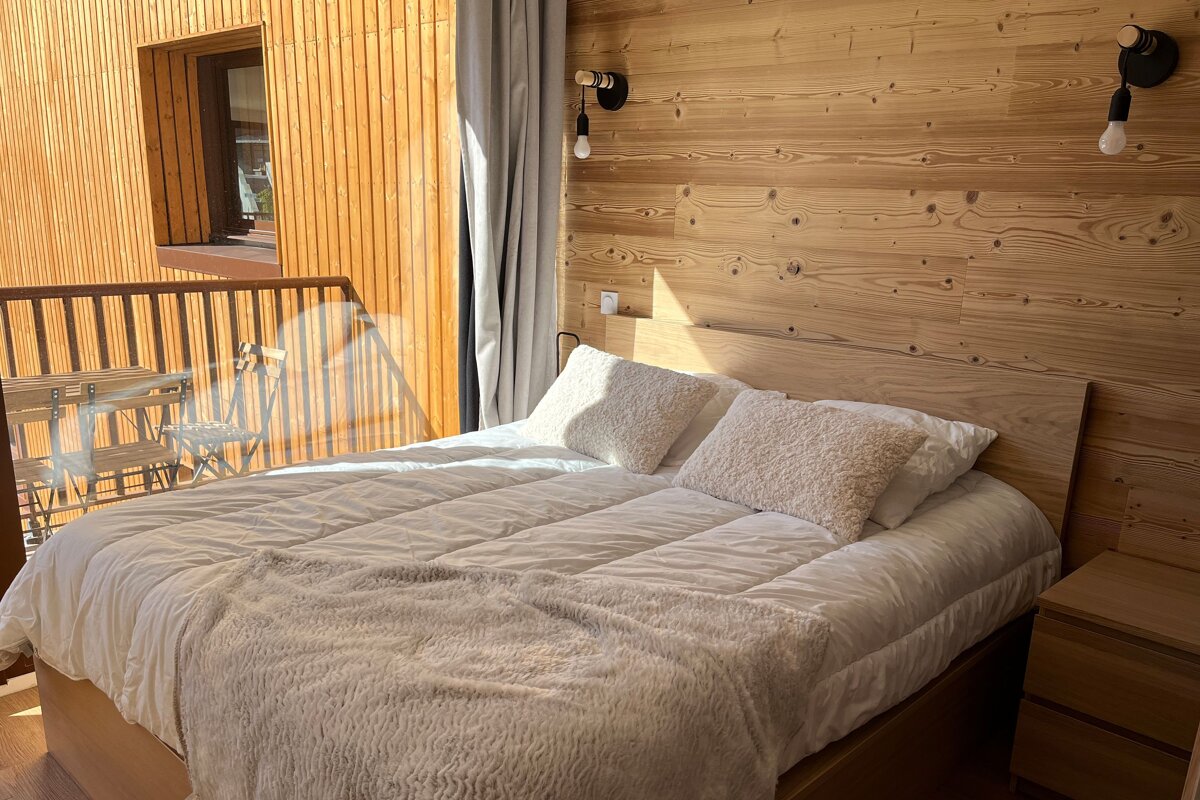 A bed with white sheets and pillows in a wooden room