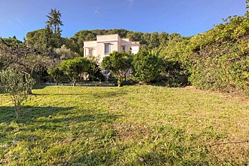A large house sits in the middle of a lush green field