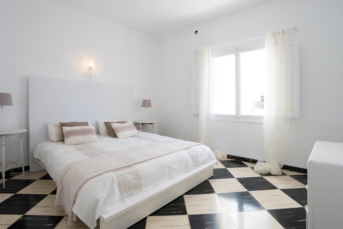 A bedroom with a white bed and a checkered floor