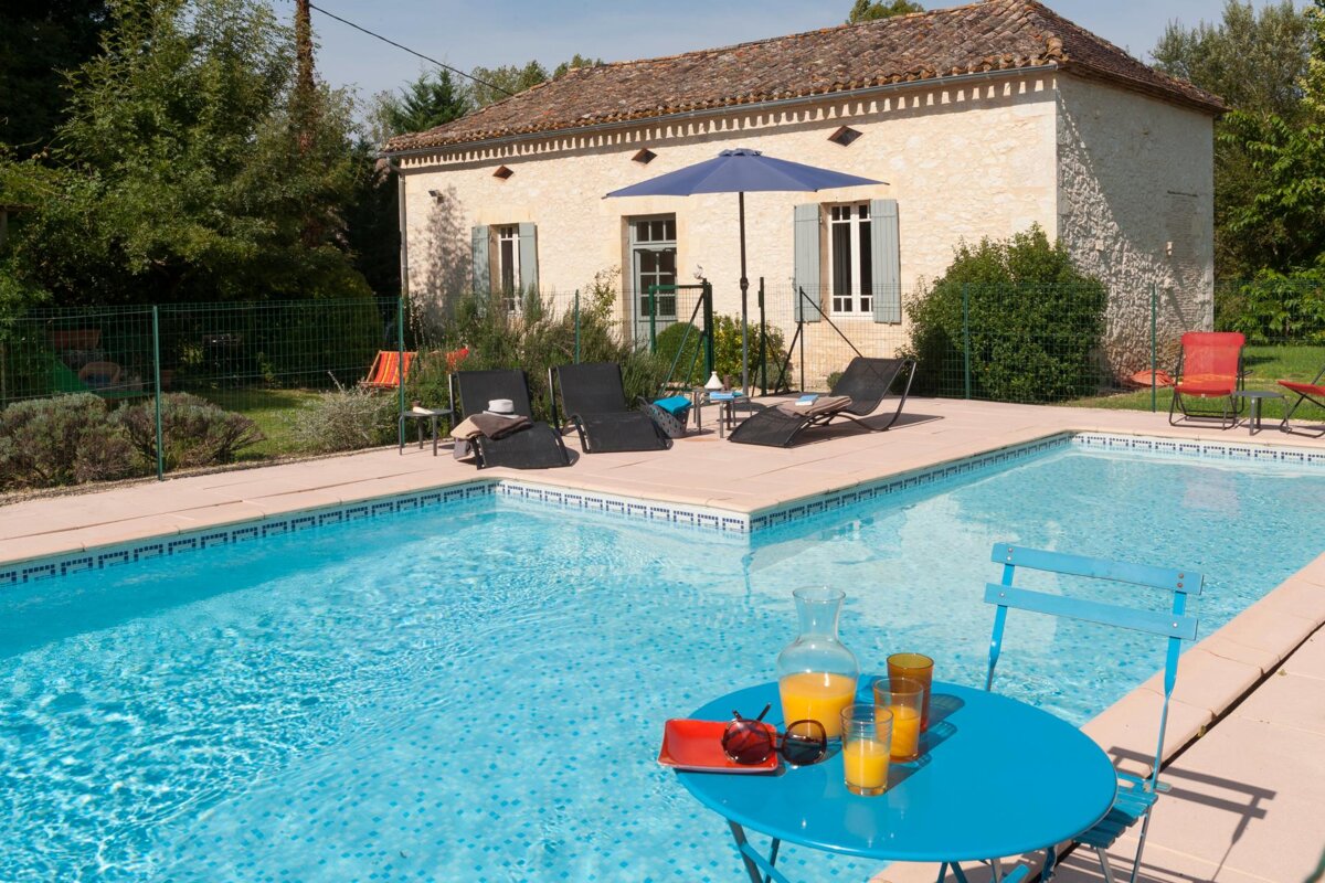 A swimming pool with a table and chairs in front of it
