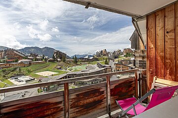 A balcony with a view of a ski resort and mountains