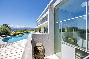 A large house with a swimming pool and mountains in the background