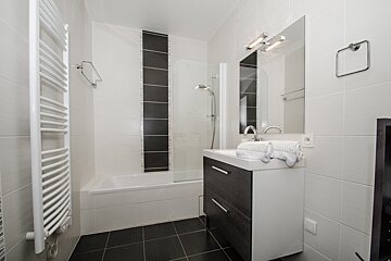 A bathroom with black and white tiles and a sink