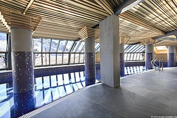 A large indoor swimming pool with a wooden ceiling
