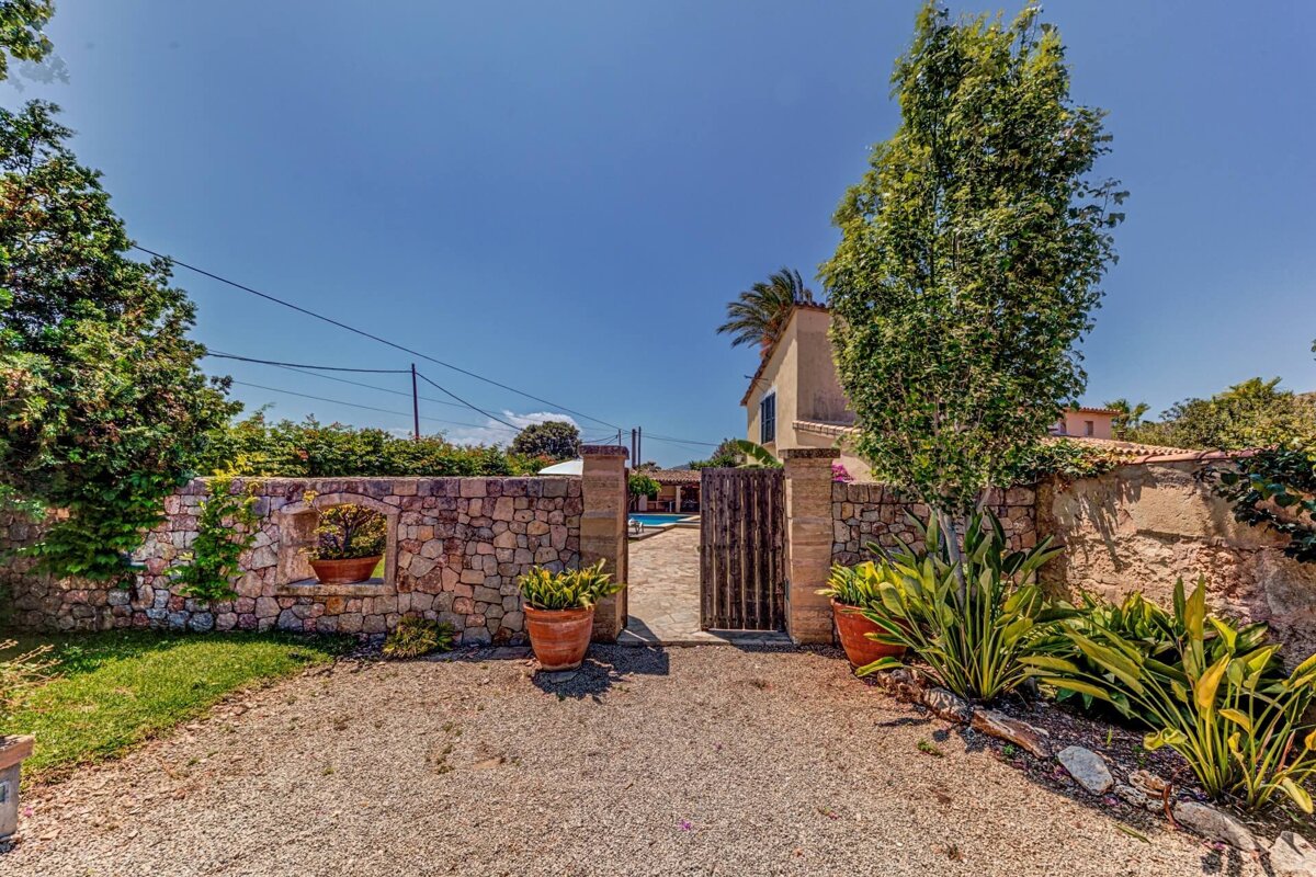 A stone wall with a gate leading to a house