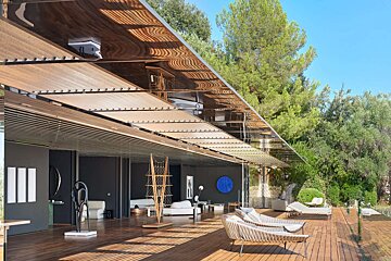 A house with a wooden deck and chairs under a canopy