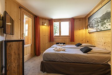 A bedroom with two beds and a television on the wall