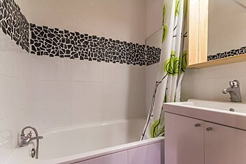 A bathroom with a green and white shower curtain