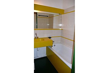 A bathroom with a yellow sink and a white bathtub