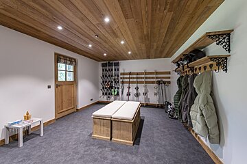 A room with a bench and skis hanging on the wall