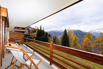A balcony with a view of the mountains and trees